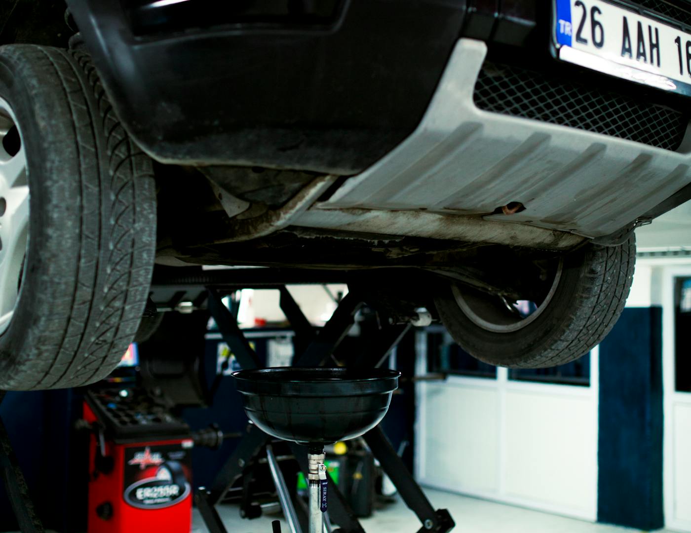 A vehicle up on the lift mid-service over an oil drain in the shop